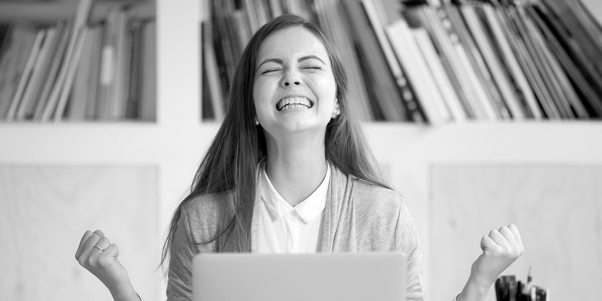 Eine junge Frau vor dem Computer freut sich über ihren Lernerfolg